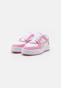 Vita och rosa sneakers med en slät läderöverdel, perforerat tånät, vita snören och tjock vit sula. Har en Puma-logotyp på sidan.