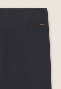 Pantaloni blu scuro caratterizzati da una trama di tessuto liscia, una cintura larga e un'etichetta metallica del marchio sul lato.