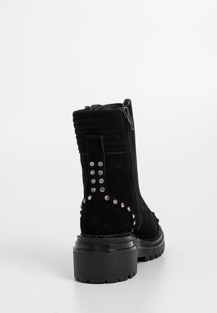 Czarny zamszowy botek na kostkę z blokowym obcasem, z zamkiem błyskawicznym i ćwiekami wzdłuż boków. Posiada żebrowane detale z tyłu.