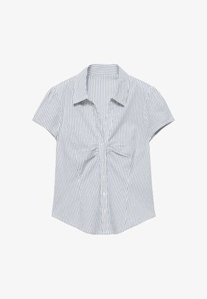 Blouse blanche à manches courtes avec fines rayures verticales bleues, boutonnée devant et détail froncé sous le col.