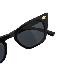 Musta kissasilmä aurinkolasit tummilla linsseillä, joissa on kiiltävä pinta ja pieni kultainen yksityiskohta nenävadissa. Suoraviivainen ja kulmikas muotoilu.