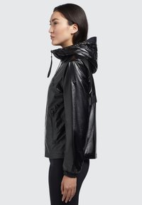 Chaqueta impermeable negra con acabado brillante, que cuenta con capucha ajustable, bolsillos laterales con cremallera y puños elásticos para un ajuste seguro.