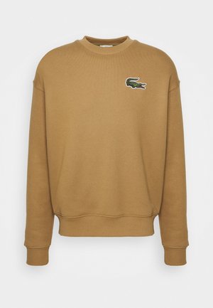Sweatshirt col rond marron chameau avec manches longues et petit logo crocodile vert sur le haut gauche de la poitrine.