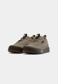 Brown outdoor shoes featuring a smooth upper material, rounded toe, and a textured rubber sole with a distinctive logo on the side.