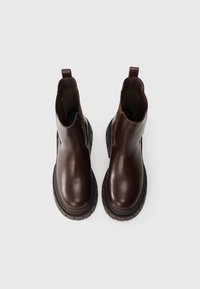 Hnědé kožené kotníkové boty s kulatými špičkami, elastickými bočními panely a silnou gumovou podrážkou s drážkováním. Pohled shora.