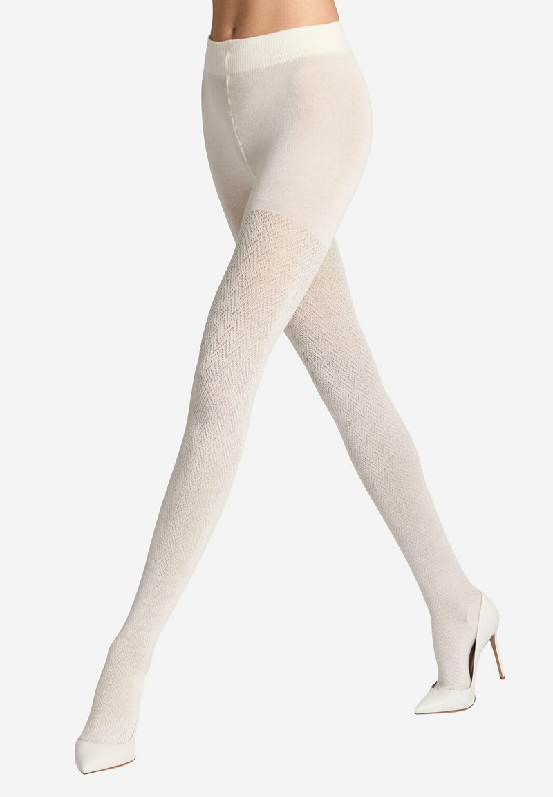 Weiße gemusterte Strumpfhosen mit einem Fischgrätenmuster, aus einem strukturierten Material, mit einem taillierten Bund, kombiniert mit weißen High Heels.