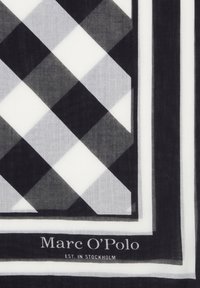 Écharpe à motif à carreaux noir et blanc en tissu léger, avec une étiquette de marque en bas et des bordures rayées contrastées.
