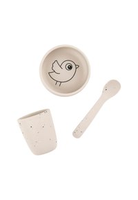 Juego de tres elementos de mesa: un bol con un gráfico de un pájaro, una taza con textura moteada y una cuchara a juego, todo en tonos beige suaves.