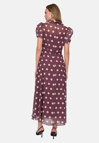 Durchscheinendes mauvefarbenes Kleid mit großen cremefarbenen Polka-Dots, kurzen Puffärmeln und einem fließenden Schnitt, mit einem geknöpften Rücken und subtiler Textur.