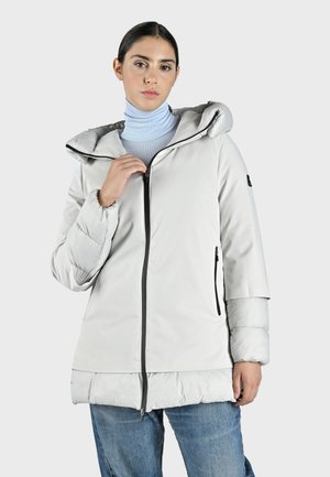 Lätt vadderad jacka i mjuk grå färg med huva, dragkedja fram och svarta detaljer. Har långa ärmar och en något längre nederdel.