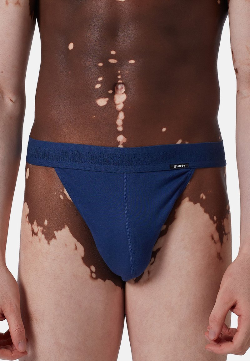 String blu per uomo realizzato in tessuto morbido, con una ampia fascia elastica in vita e un design minimalista con texture liscia.
