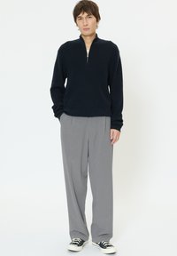 Meresinise poollukuga pehme kangaga pullover, kombineeritud helehallide laiade pükstega ja mustade madalate tossudega. Lihtne disain, lõdvestunud istuvus.