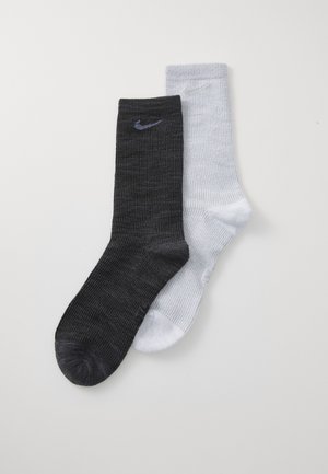 Sorte og hvide atletiske sokker, ribbet tekstur, med et logo på hver sok. Den sorte sok er ensfarvet, mens den hvide sok har et subtilt mønster.