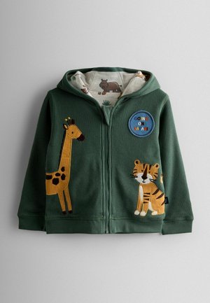 Grüne Corduroy-Zip-Hoodie mit Giraffen- und Tiger-Applikationen, gefüttert mit einem Safari-Themenstoff und mit einem runden Patch "AUF SAFARI GEHEN".