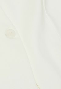 Witte stof met een zachte textuur, voorzien van een ronde, transparante knop en een glad, op maat gemaakt ontwerp.