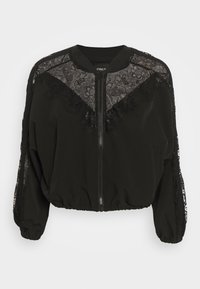 Black bomber jacket with lace accents on shoulders and front. Features a zip closure, elastic cuffs, and a cropped design. Soft fabric texture.