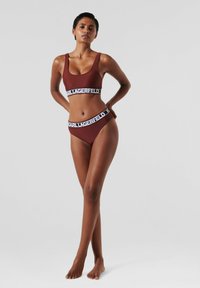 Bikini set v hlbokej burgundskej farbe, vyrobený z hladkej textílie, s širokým čiernym pásom so značkou "Karl Lagerfeld".