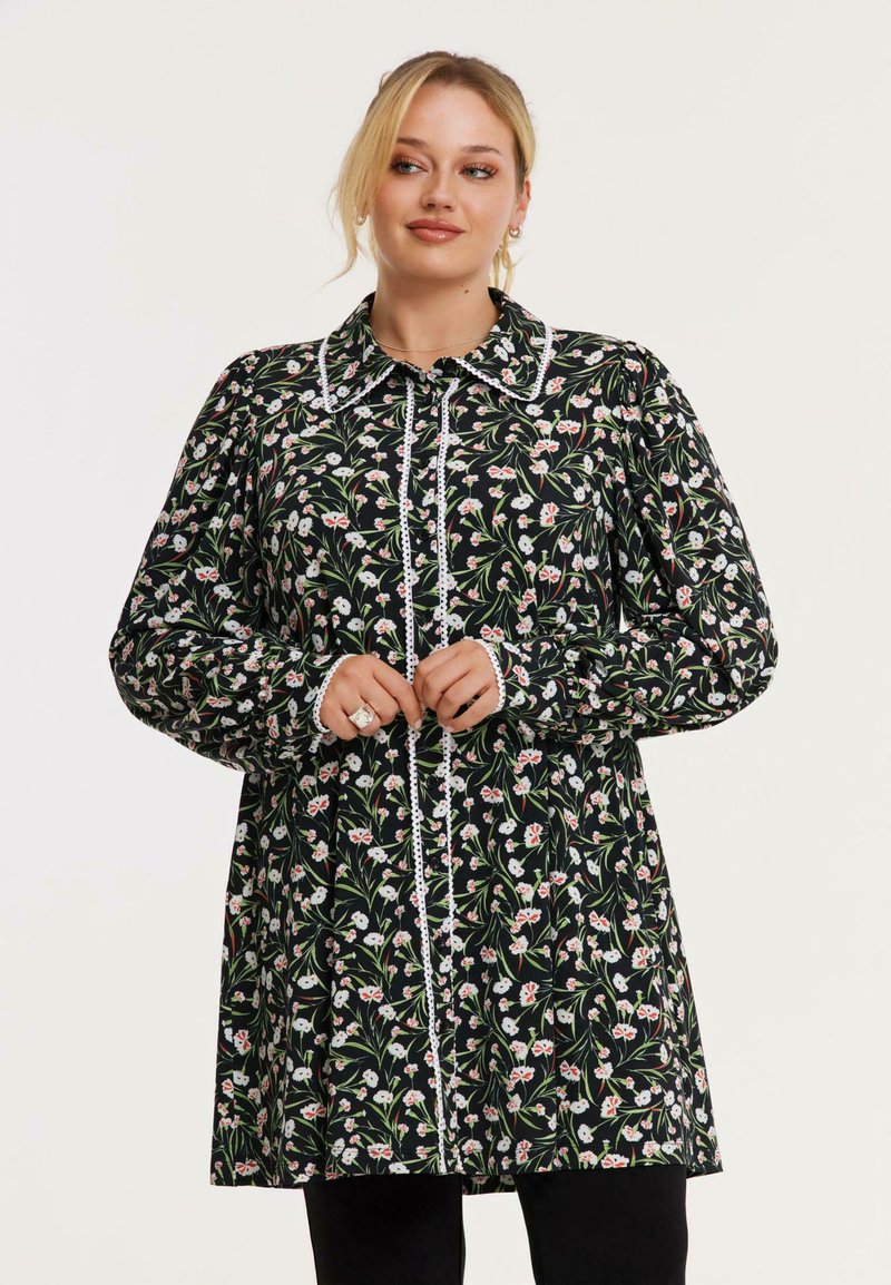 Schwarzes Blumenkleid mit langen Puffärmel, weißem Rand und Knopfverschluss. Es zeigt ein Blumenmuster mit roten und weißen Akzenten.