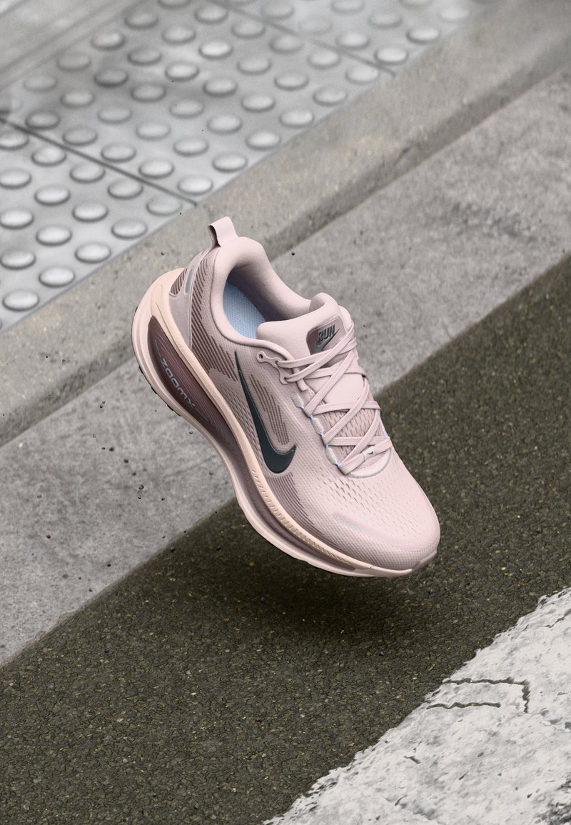 Jasnoróżowe buty do biegania z siateczkową cholewką, wyściełanym kołnierzem i gumową podeszwą. Zawierają turkusowy znak Nike Swoosh oraz subtelne logo na języku.