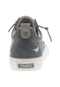 Baskets en cuir gris avec une semelle en caoutchouc blanc, présentant un petit logo et des détails de couture au niveau du talon et des côtés.