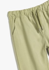 Lichtgroene joggingbroek met een elastische tailleband, trekkoord, zijzakken en een gladde textuur. Eenvoudig ontwerp zonder zichtbare patronen.