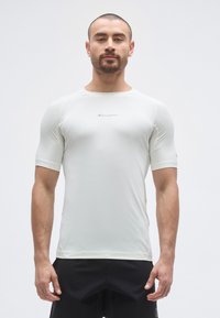 T-shirt de sport léger et ajusté en tissu blanc doux, avec manches courtes et col rond ; comprend un petit logo sur la poitrine.