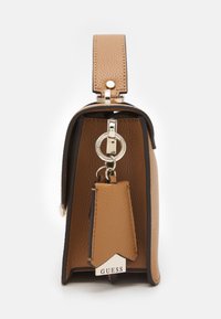 Beżowa torebka ze skóry syntetycznej o strukturalnym kształcie, z srebrnym breloczkiem i fakturowaną powierzchnią.