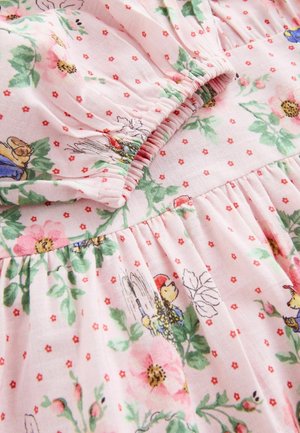 Lyserødt stof med elastisk manchet, dekoreret med grønne blade, små røde blomster og tegneseriefigurer i farverige outfits.