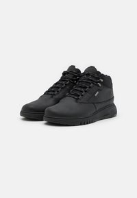 Scarpe nere alte in pelle texturizzata con colletto imbottito, dotate di lacci neri e suola in gomma con un motivo di battistrada distintivo.