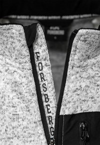 Grijze en zwarte fleecejack met ritssluiting en hoge kraag. Het label "FORSBERG" is op de binnenkant van de nek gestikt. Dit jack heeft een soepele textuur en een modern ontwerp.