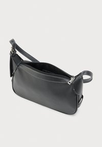 Sac à bandoulière en cuir noir avec fermeture éclair, forme incurvée, surpiqûres blanches contrastantes et sangle réglable pour une utilisation polyvalente.