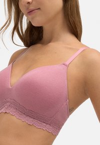 Sujetador de canalé rosa con escote en V, tirantes finos ajustables y un borde de encaje en la parte inferior. Textura suave y diseño ajustado.