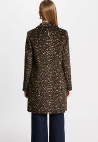 Cappotto leopardato con una base marrone scuro e macchie color beige chiaro, colletto e maniche lunghe. Cucitura orizzontale sulla schiena.