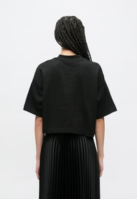 Μαύρο cropped t-shirt με κοντά μανίκια και στρογγυλή λ�αιμόκοψη, σε συνδυασμό με μαύρη πλισέ φούστα, με απαλό υφάδι.