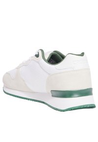 Chaussure de sport blanche et verte en mesh et suède, avec un col rembourré, des lacets plats et une semelle en caoutchouc texturée.