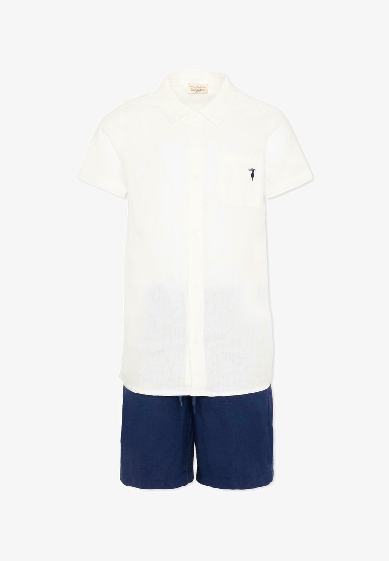 Chemise blanche à manches courtes avec col et poche, associée à un short bleu foncé, présentée sur fond blanc.