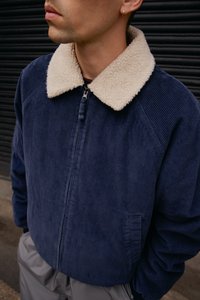 Marineblå fløjl jakke med en beige faux shearling krave, lynlås lukning og sidelommer. Tekstureret stof med lodrette ribber.