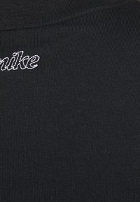 La tela de la camiseta de algodón negra presenta una textura acanalada, con "Nike" bordado en hilo blanco en el cuello.