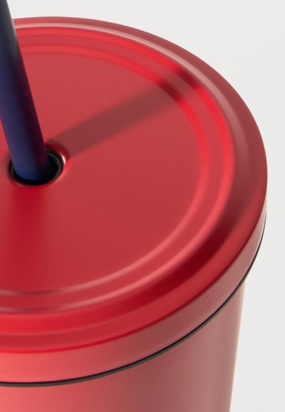 Κυλινδρικό κόκκινο δοχείο με ένα σκούρο μπλε καλαμάκι που έχει τοποθετηθεί μέσα από μια κεντρική τρύπα στο καπάκι, με λευκό φόντο.
