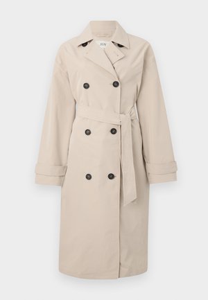 Beige trench kabát dupla gombolású elülső résszel és fekete gombokkal. Széles hajtókák, övvel ellátott derék és hosszú ujjú, galléros kivitel jellemzi.