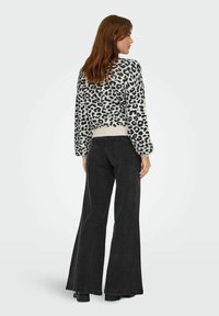 Leopardmönstrad tröja i svart och kräm, med ribbat avslut, i kombination med högmidjade svarta utsvängda jeans. Mjuk textur, avslappnad passform.