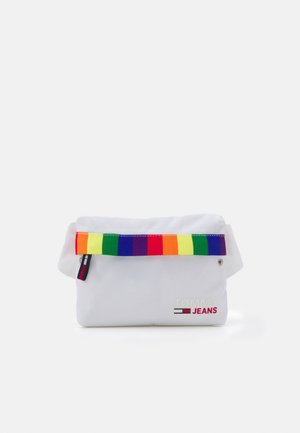 Hvid canvas taske med en farverig regnbue-striped rem. Har et lille logo "TOMMY JEANS" i rødt. Kompakt, fold-over design.