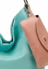 Sac à main en tissu bleu clair avec une texture douce et un design décontracté, comprenant une petite pochette en cuir rose fixée par un crochet.