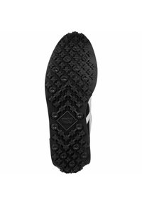 Semelle de chaussure en caoutchouc noir présentant un motif de grip moulé avec des clous circulaires et en forme de fleur. Surface texturée avec un détail de logo en forme de diamant.