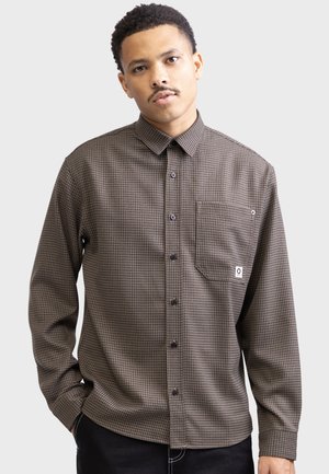 Brown checkered long-sleeve button-up shirt, featuring a pointed collar, a chest pocket, and black buttons. Made of textured fabric.