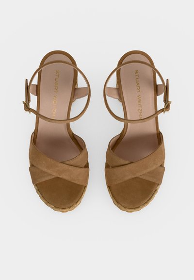 Paire de sandales ouvertes en daim beige avec des brides croisées, des boucles à la cheville et des semelles compensées espadrilles tressées, vues de dessus.