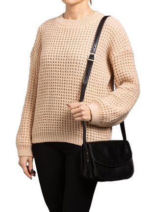 Maglione beige lavorato a maglia con un motivo testurizzato, abbinato a una borsa a tracolla in pelle nera, con tracolla e chiusura a pattina.