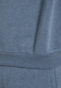 Blauer Fleece-Stoff mit weicher Textur, geripptem Bund und einem dezenten melierten Muster. Ideal für die Freizeit.