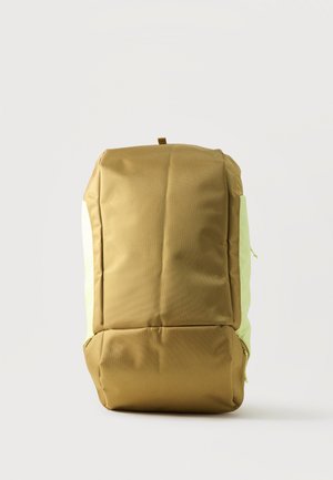 Sac à dos rectangulaire bicolore vert olive et jaune clair avec poignée supérieure, poche avant et design matelassé structuré sur fond blanc.