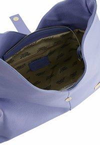 Helle lila Ledertasche mit strukturiertem Äußeren, goldenen Beschlägen und einem geräumigen beigen Innenraum, der ein Logomuster und eine Reißverschlusstasche aufweist.